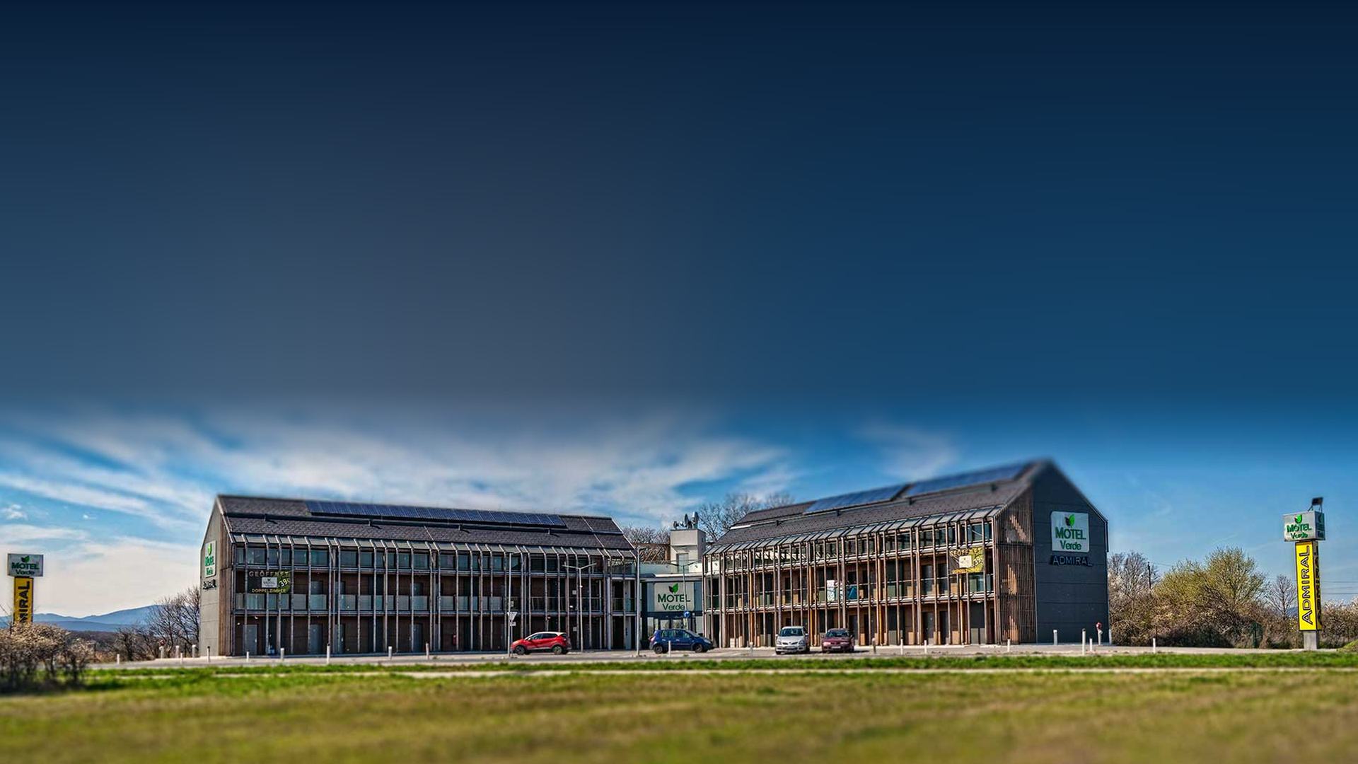 Motel Verde in Schönau an der Triesting – Neubau in Modulbauweise von C4 Projekt: zwei dreigeschoßige Gebäude mit Holzlamellen-Fassade unter blauem Himmel