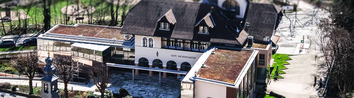 Luftaufnahme des Hotel Sacher in Baden mit Café Sachergarten, Gründächern und Vorplatz